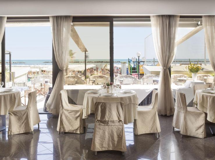 Ristorante elegante con vista mare e tavoli apparecchiati.